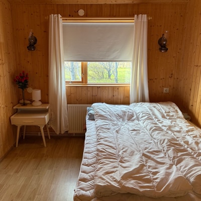 Lichtdurchflutetes Schlafzimmer mit Doppelbett und Holzwänden