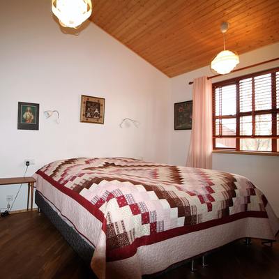 Cozy double bed under wooden ceiling and sloping ceiling